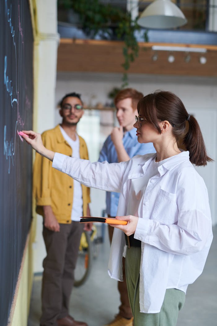 Overcoming Challenges Lessons Every Entrepreneur Must Learn A group of young people discussing ideas at a blackboard in a modern office setting.